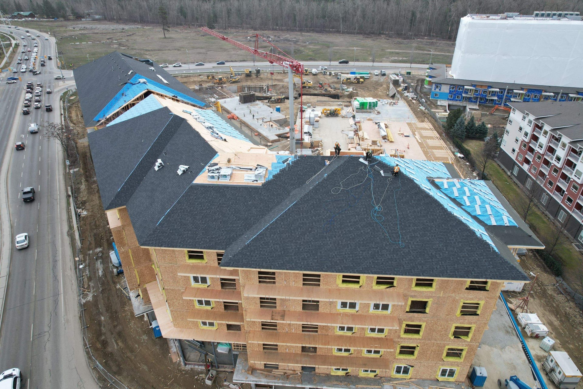Aerial view of a multi-storey building under construction, its roof being shingled