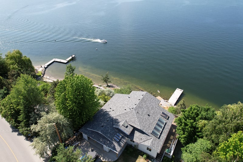 Completed asphalt shingle roof on a lakefront home with its dock on Okanagan Lake
