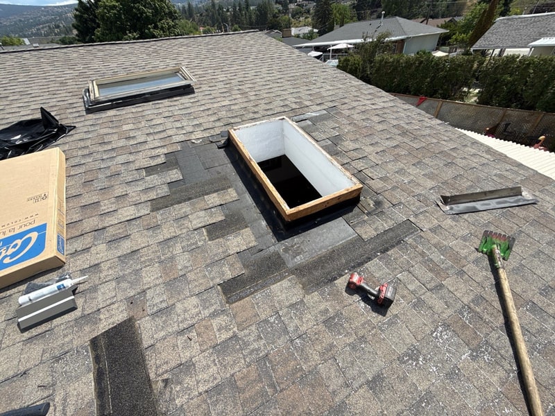 Skylight opening mid-install: framed in wood with membrane around it, the old unit and tools on the roof beside it