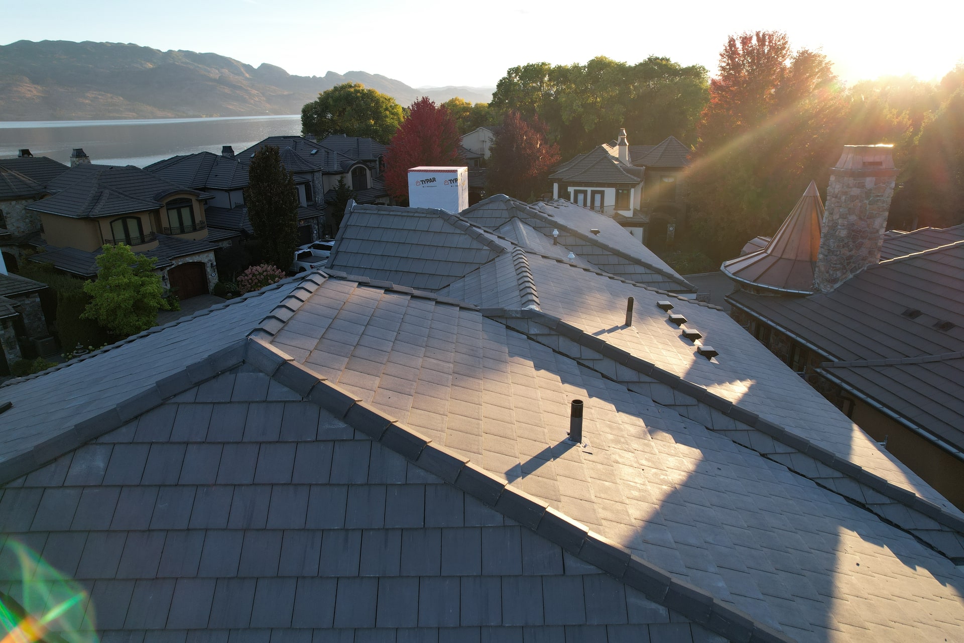 The finished concrete tile roof in low sun, the lake and the hills beyond