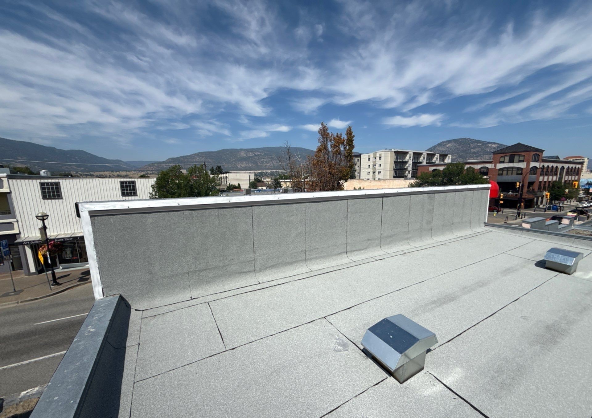 New granulated torch-on roof and parapet on a downtown building, the hills behind