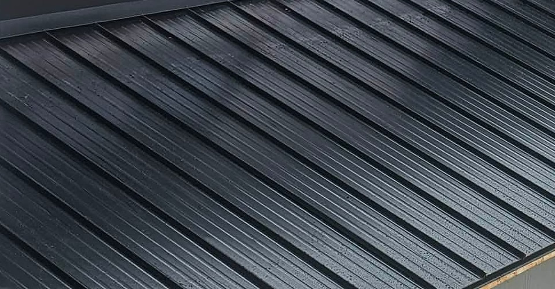 Black metal roof panels on a new home, beaded with rain
