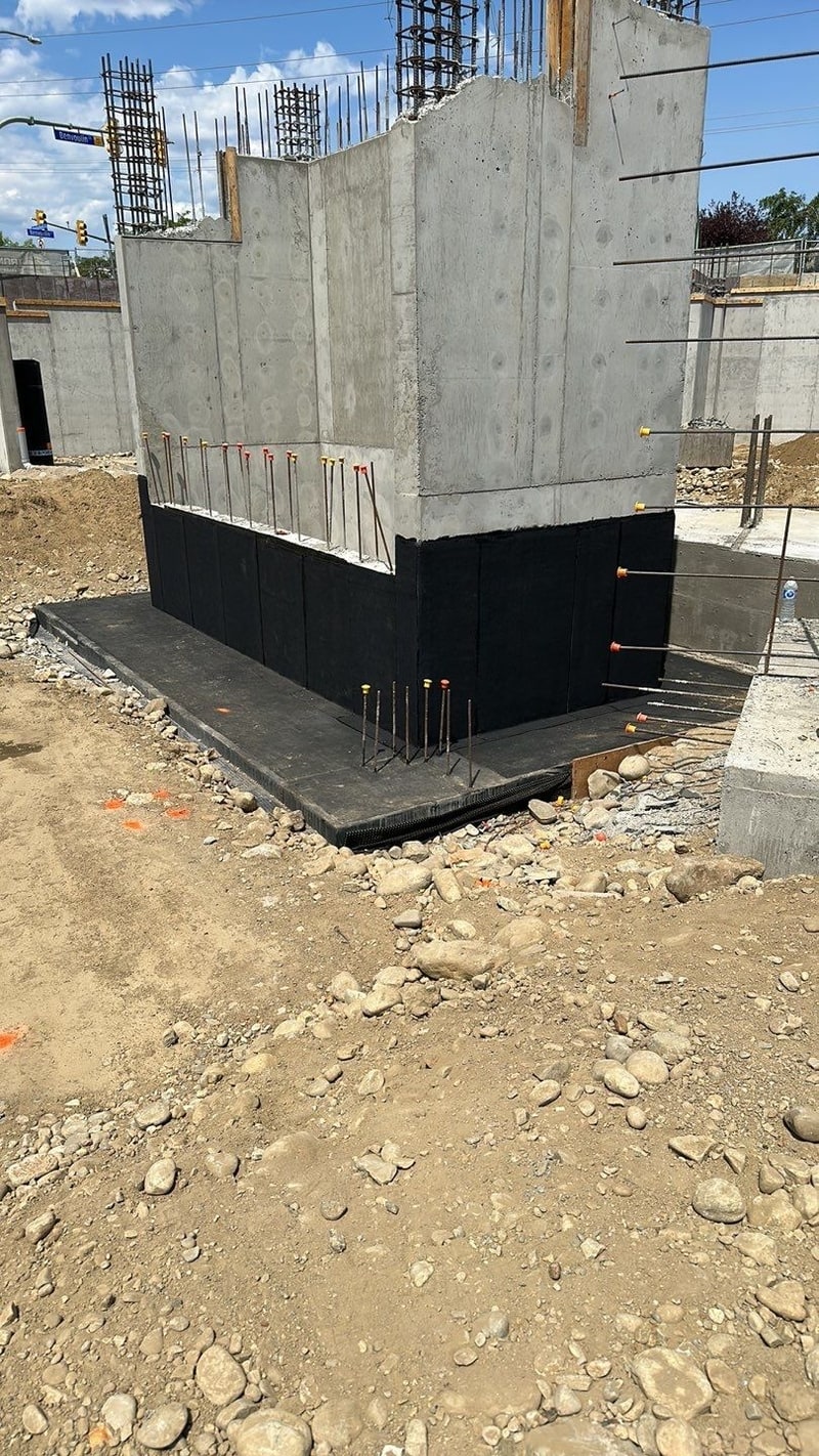Concrete elevator shaft with black membrane on its lower walls and over its base